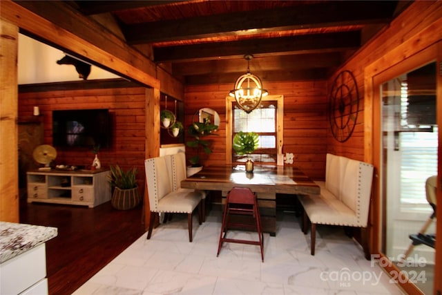 dining room featuring beamed ceiling, a notable chandelier, wooden walls, and light hardwood / wood-style flooring