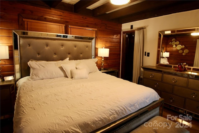 bedroom with beam ceiling and wooden walls