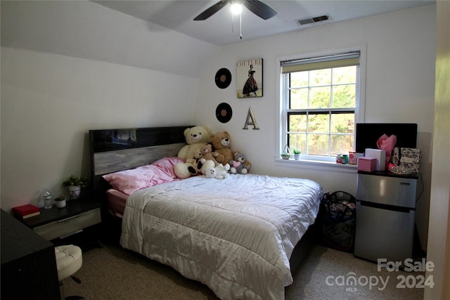 bedroom with ceiling fan, stainless steel fridge, light colored carpet, and vaulted ceiling