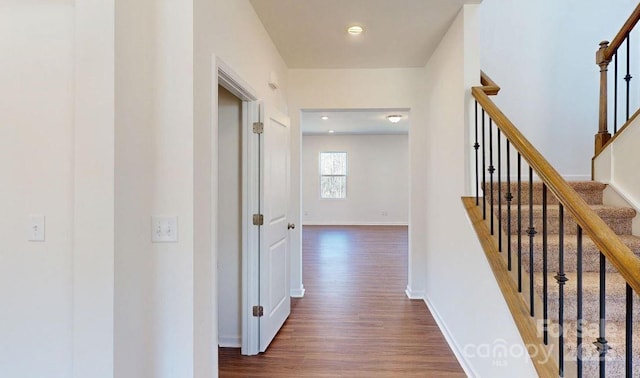 corridor with stairway, dark wood finished floors, and baseboards