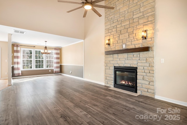 unfurnished living room featuring ceiling fan with notable chandelier, a fireplace, dark hardwood / wood-style floors, and a high ceiling