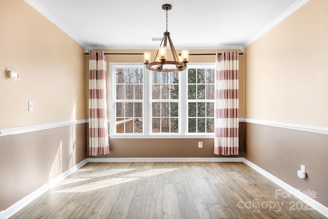 unfurnished dining area featuring a notable chandelier, crown molding, and light hardwood / wood-style floors