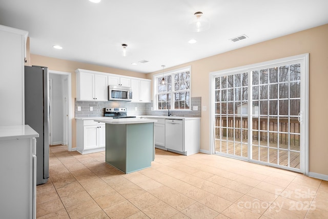 kitchen featuring white cabinetry, backsplash, a center island, and appliances with stainless steel finishes