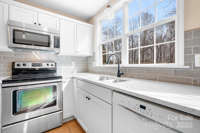 kitchen featuring white cabinetry, sink, backsplash, light stone counters, and stainless steel appliances