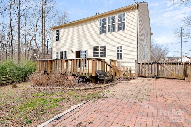 rear view of house featuring a wooden deck and a patio area