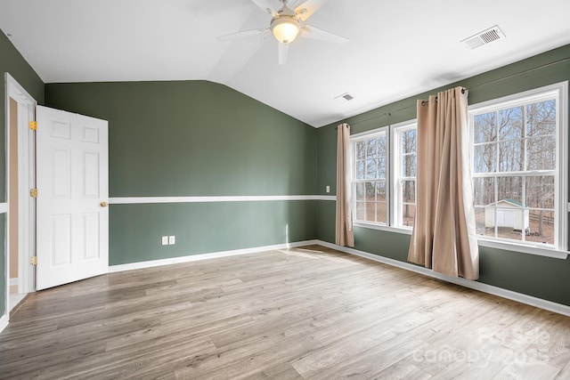 spare room featuring ceiling fan, lofted ceiling, wood-type flooring, and plenty of natural light