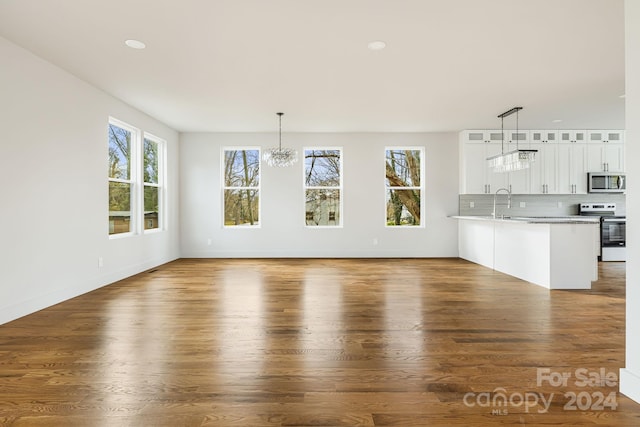 unfurnished living room with dark hardwood / wood-style floors, a healthy amount of sunlight, and a chandelier