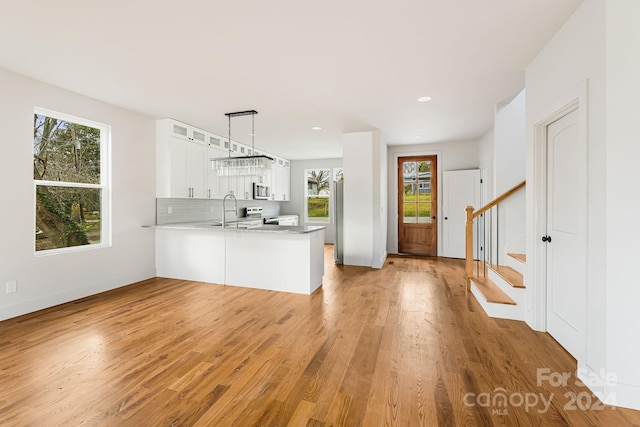 kitchen with pendant lighting, white cabinets, kitchen peninsula, and a wealth of natural light