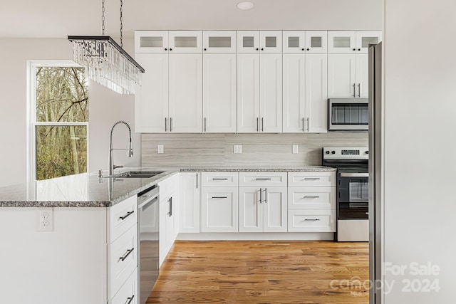 kitchen with white cabinetry, sink, stainless steel appliances, and light hardwood / wood-style floors