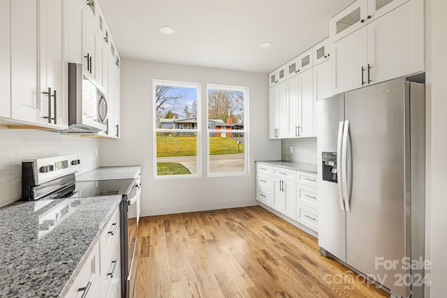 kitchen with backsplash, light stone counters, stainless steel appliances, light hardwood / wood-style floors, and white cabinetry