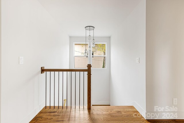 stairs with hardwood / wood-style floors and a notable chandelier