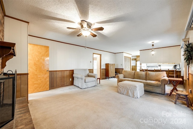 carpeted living room featuring ceiling fan, ornamental molding, and a textured ceiling