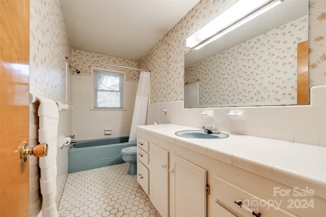 full bathroom with shower / tub combo, tile patterned floors, vanity, tile walls, and toilet