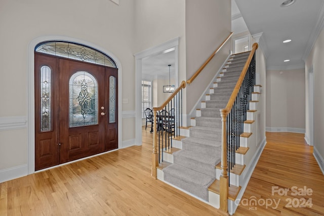 foyer entrance with a chandelier, a high ceiling, hardwood / wood-style flooring, and ornamental molding