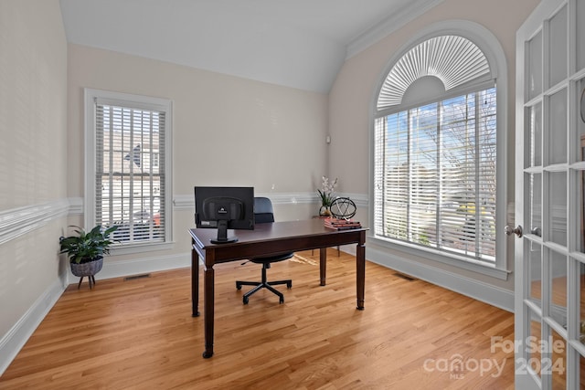 office space with lofted ceiling, light hardwood / wood-style floors, a wealth of natural light, and ornamental molding