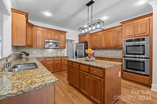 kitchen featuring sink, a center island, stainless steel appliances, light hardwood / wood-style flooring, and decorative light fixtures