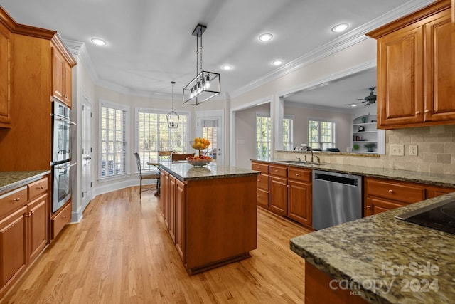 kitchen with light wood-type flooring, plenty of natural light, stainless steel appliances, a kitchen island, and hanging light fixtures