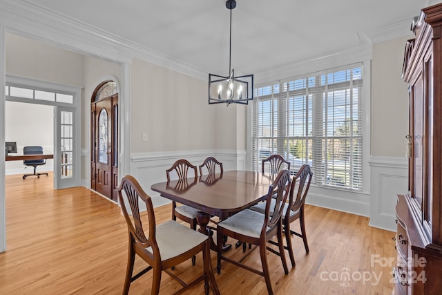 dining room with a notable chandelier, light wood-type flooring, crown molding, and french doors