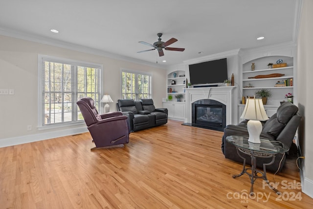 living room with crown molding, light hardwood / wood-style flooring, and built in features