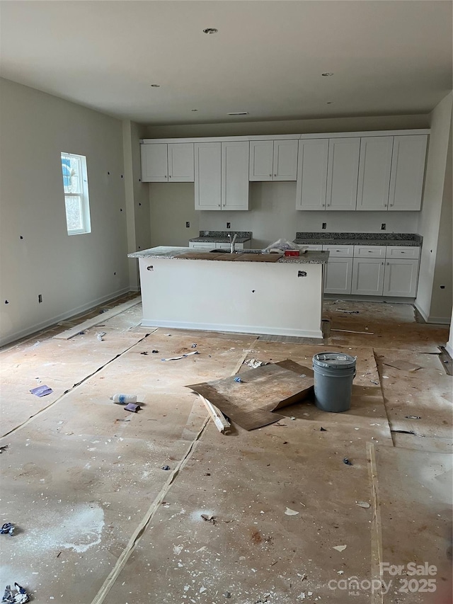 kitchen featuring sink, white cabinets, and an island with sink