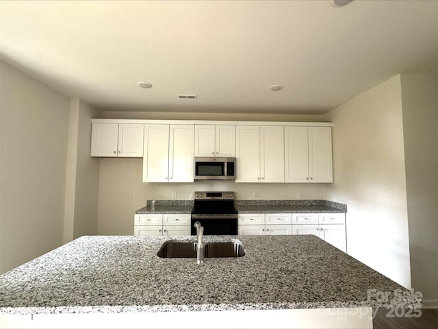 164 Wildwood Loop, Statesville, NC 28677 - kitchen with dark stone countertops, a sink, white cabinetry, appliances with stainless steel finishes, and visible vents