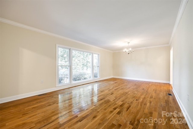 unfurnished room with hardwood / wood-style floors, a notable chandelier, and ornamental molding