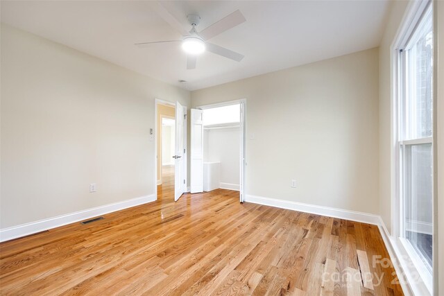 unfurnished bedroom with ceiling fan, a closet, and light wood-type flooring