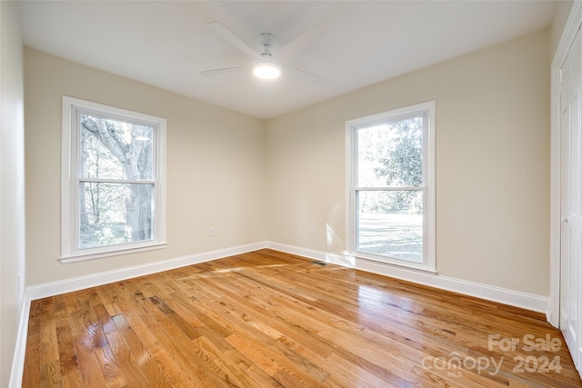 spare room with light wood-type flooring, ceiling fan, and a healthy amount of sunlight