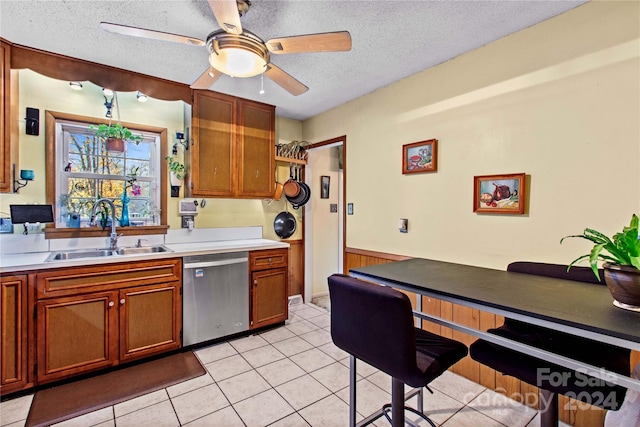 kitchen featuring a textured ceiling, dishwasher, light tile patterned flooring, and sink