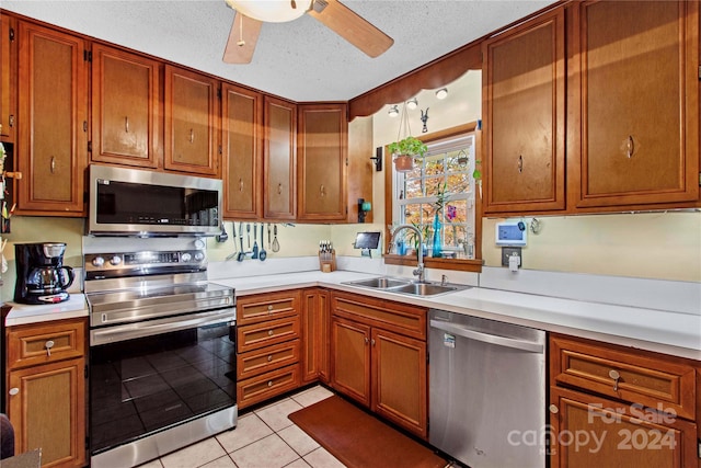 kitchen featuring appliances with stainless steel finishes, a textured ceiling, light tile patterned floors, and sink