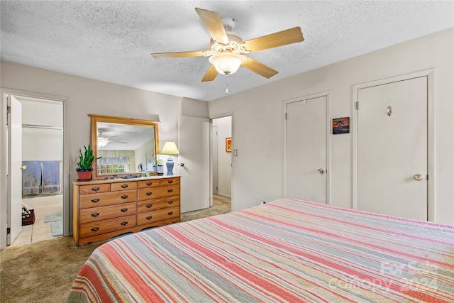 carpeted bedroom with ensuite bath, ceiling fan, and a textured ceiling