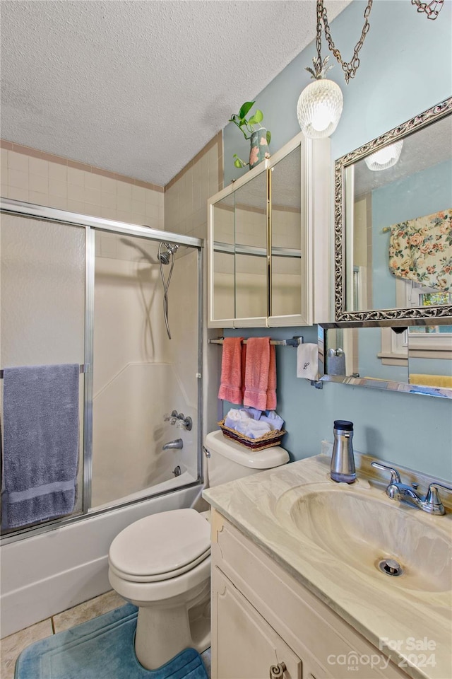 full bathroom with vanity, shower / bath combination with glass door, tile patterned flooring, toilet, and a textured ceiling