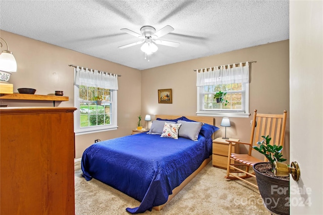 bedroom with ceiling fan, light carpet, and a textured ceiling