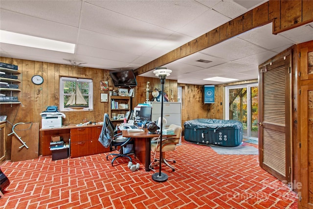 office space featuring wood walls, plenty of natural light, and a drop ceiling