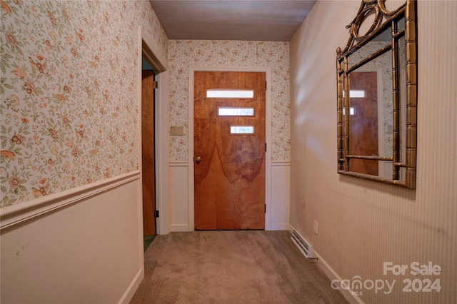 doorway with a textured ceiling and carpet floors