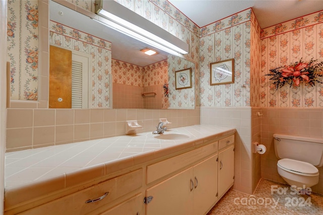 bathroom with tile patterned floors, vanity, tile walls, and toilet