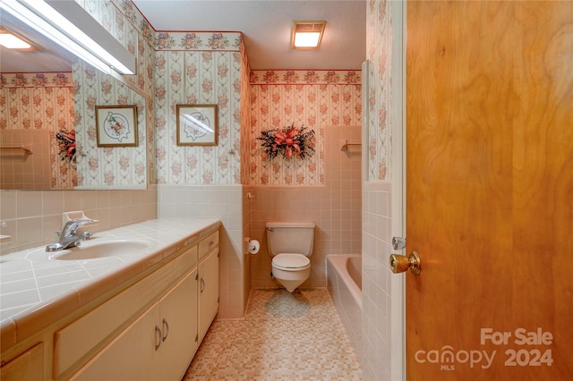 bathroom featuring a textured ceiling, vanity, toilet, and tile walls