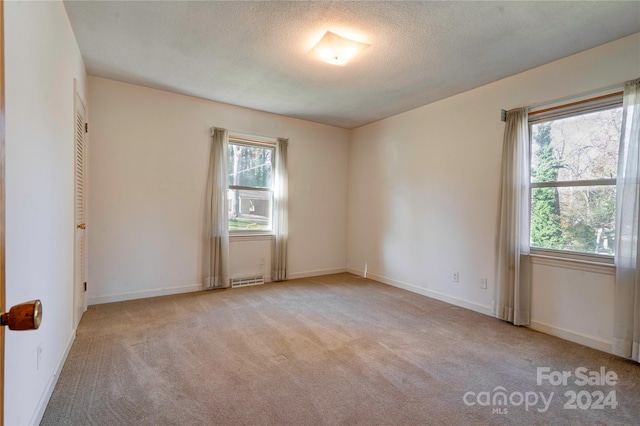 empty room with a textured ceiling and light carpet