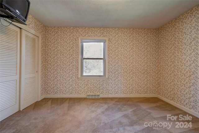 unfurnished bedroom featuring a closet, carpet floors, and a textured ceiling