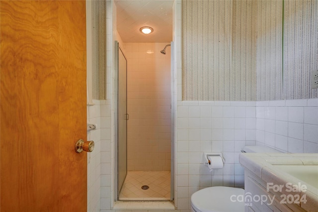 bathroom featuring vanity, toilet, walk in shower, and tile walls