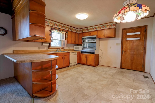 kitchen with a textured ceiling, white appliances, decorative light fixtures, and sink