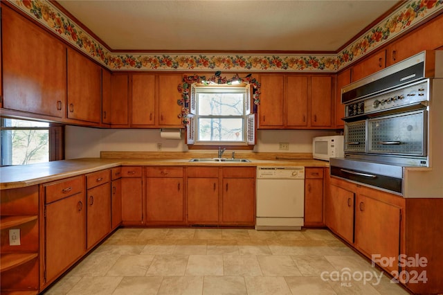 kitchen with plenty of natural light, white appliances, and sink