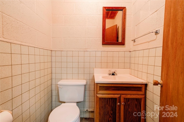 bathroom featuring vanity, toilet, and tile walls