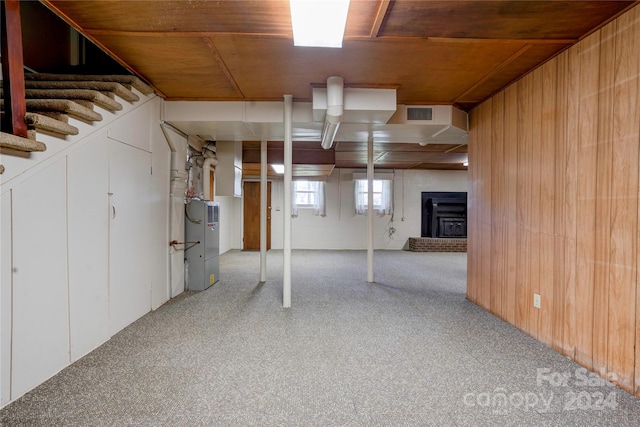 basement with a wood stove, wood walls, and light colored carpet