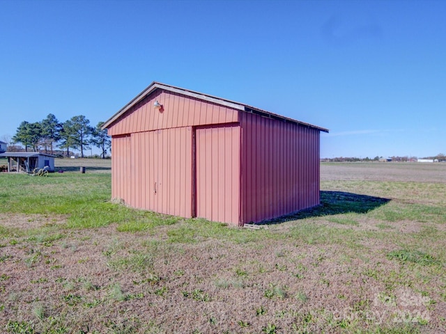 view of outbuilding with a rural view and a yard