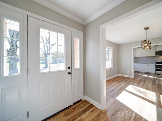 entryway with ornamental molding, light wood-type flooring, and a healthy amount of sunlight