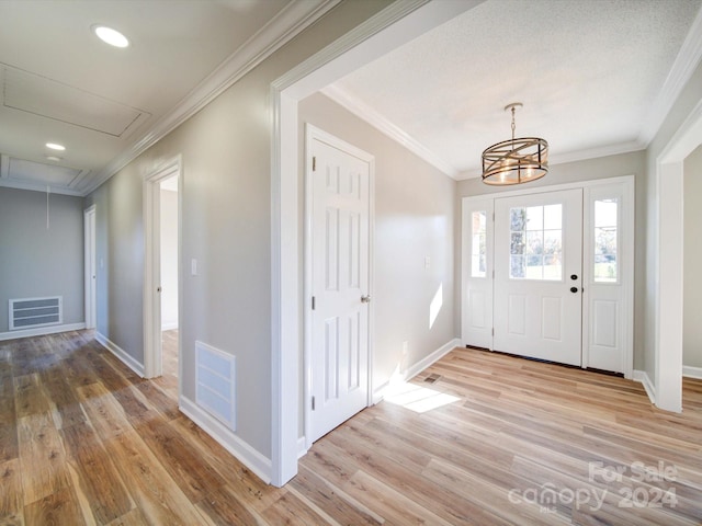 foyer featuring light hardwood / wood-style floors, crown molding, and a chandelier