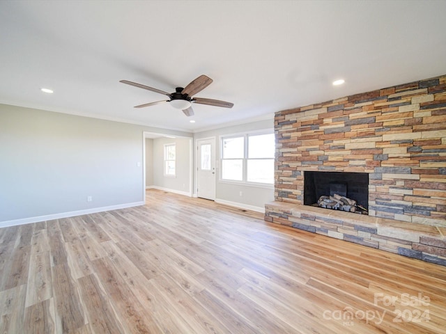 unfurnished living room with ceiling fan, light hardwood / wood-style floors, ornamental molding, and a fireplace