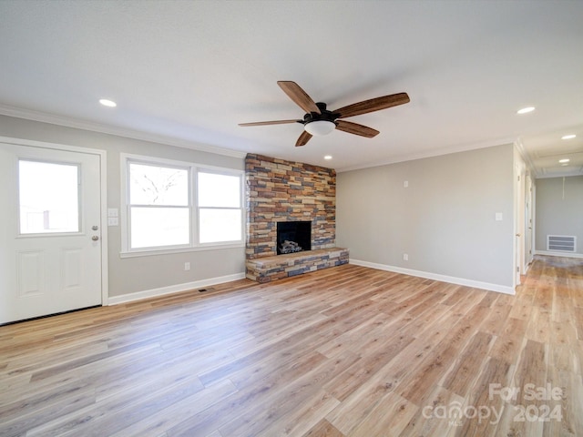 unfurnished living room featuring light hardwood / wood-style flooring, ceiling fan, a stone fireplace, and crown molding