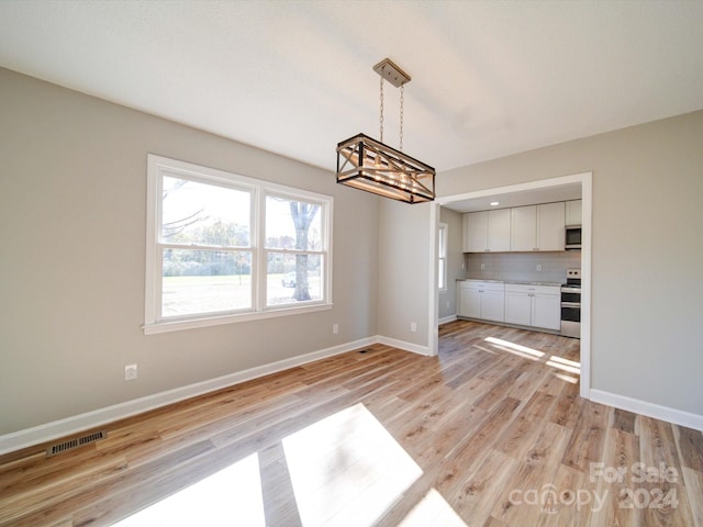 unfurnished dining area featuring light hardwood / wood-style floors and an inviting chandelier